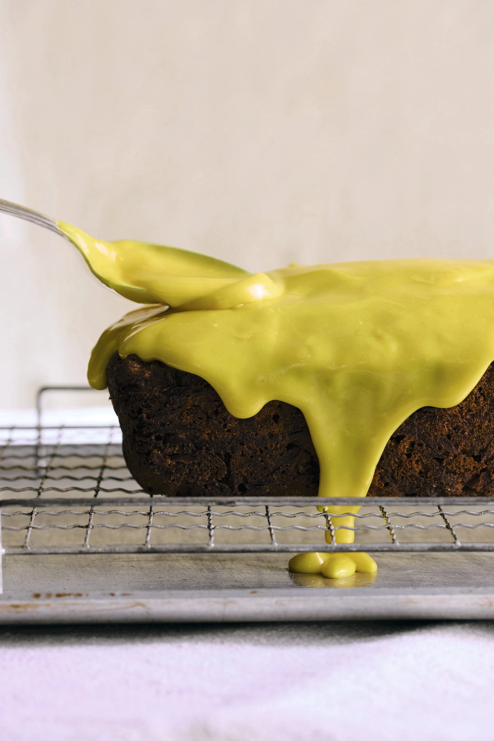 Carrot cake with lemon turmeric icing being spooned over the loaf