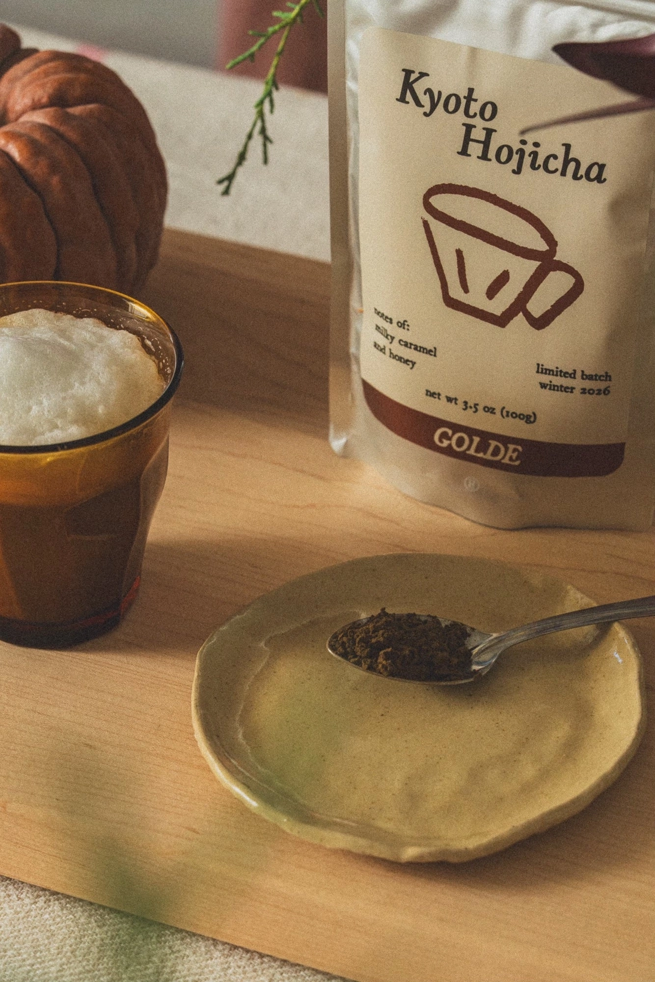 Kyoto Hojicha powder on a plate beside a glass and the pouch